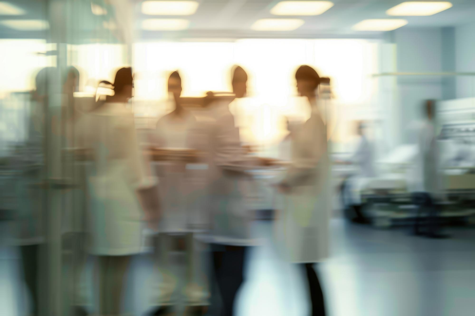 Harley Street Clinic 7 Blurred group of healthcare staff in white coats gathered in a hospital corridor or clinical room.