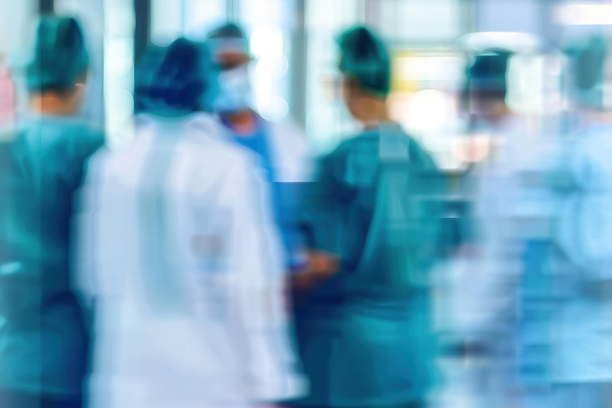 Ezra Mega Case Study 3 Blurred group of medical staff in scrubs and lab coats standing together in a hospital setting.