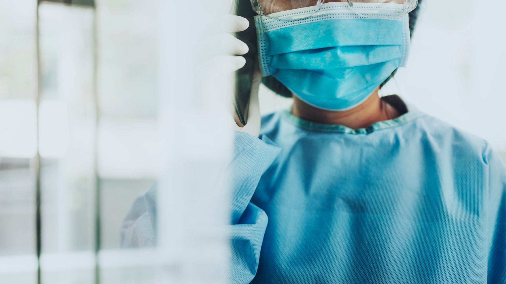 FutureNHS 8 Clinician wearing protective mask, gloves and gown while speaking on a phone.